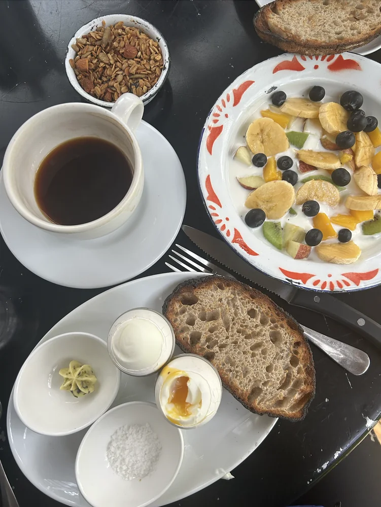 Breakfast of coffee, fruit and yoghurt, sourdough toast and a soft-boiled egg